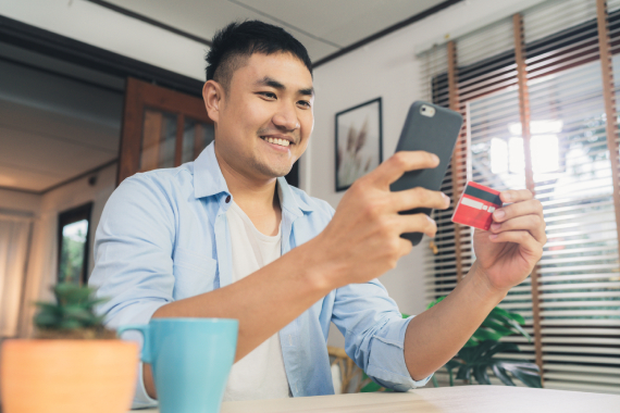 Man holding a card typing on phone